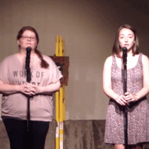 Vocal coach Meg O'Brien guiding a student during a duet performance on stage.
